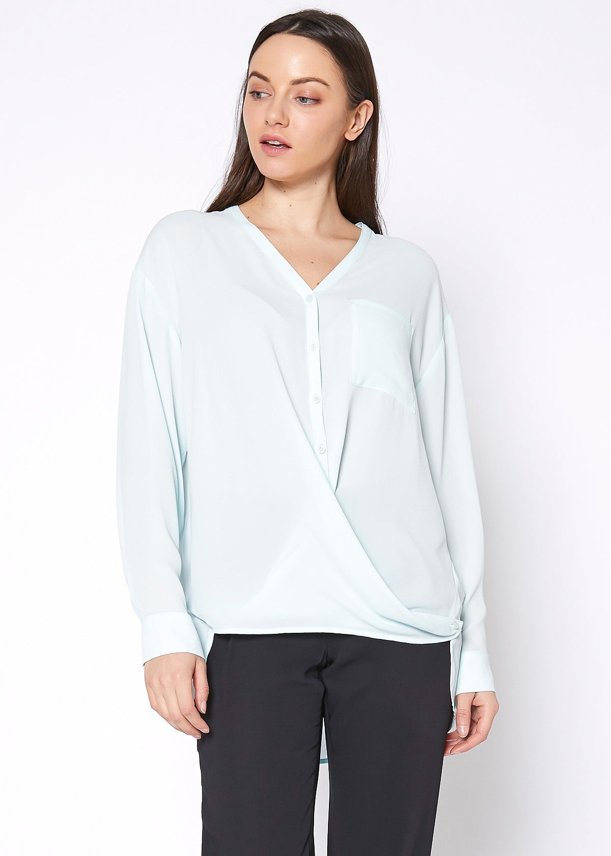 A stylish V-Neck Wrap Hem Blouse featuring a pleated front and hi-lo design, with long sleeves and single button cuffs, made from 100% polyester.