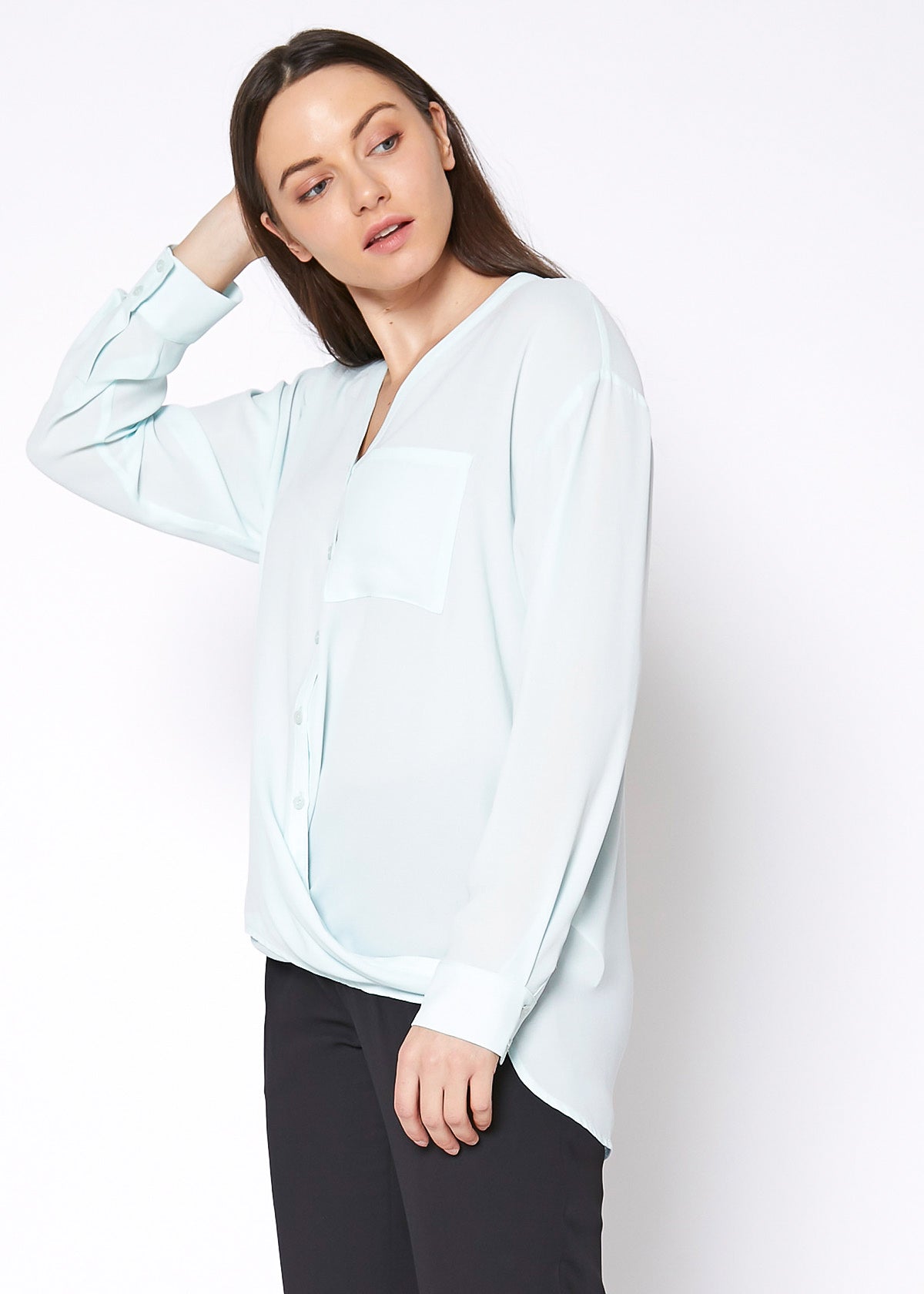 A stylish V-Neck Wrap Hem Blouse featuring a pleated front and hi-lo design, with long sleeves and single button cuffs, made from 100% polyester.