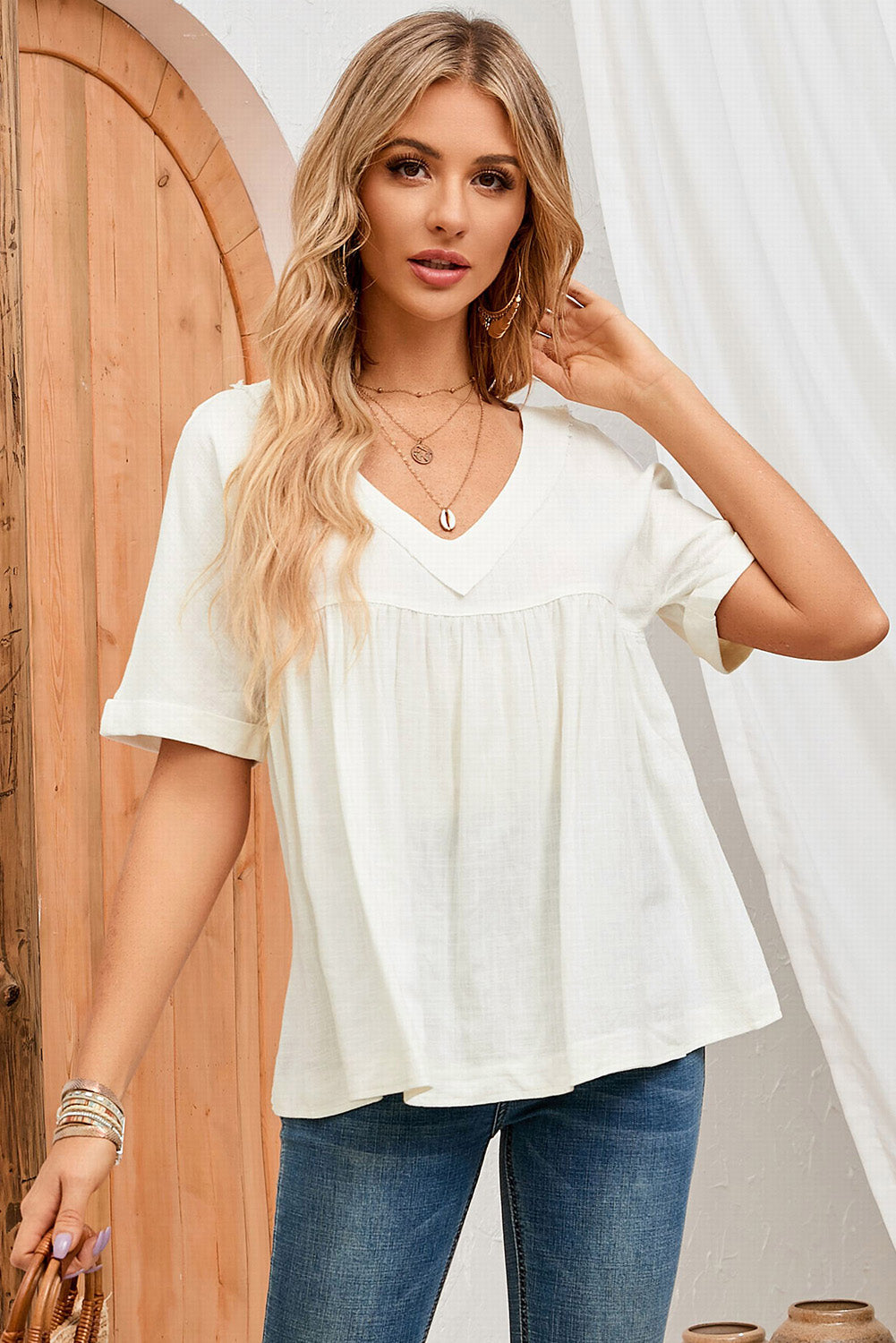 A stylish white babydoll blouse featuring frayed details, ruffled design, and rolled short sleeves, perfect for spring and summer wear.