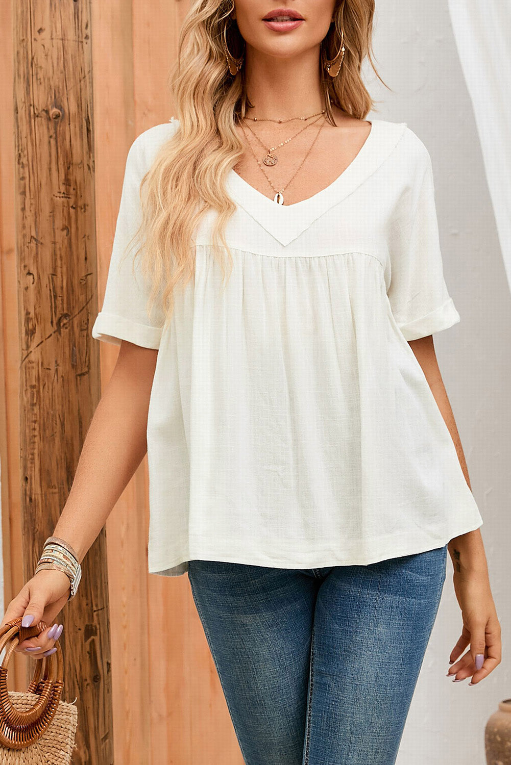 A stylish white babydoll blouse featuring frayed details, ruffled design, and rolled short sleeves, perfect for spring and summer wear.