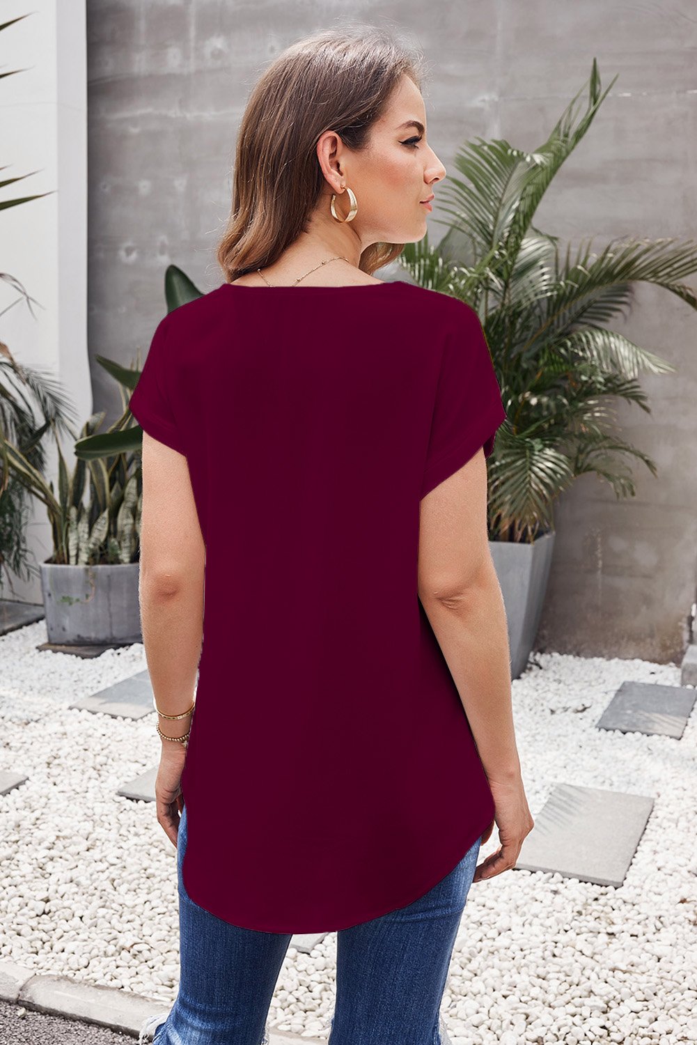 Women wearing a red short sleeve blouse with a gold zipper detail, showcasing a relaxed fit and high-low hemline.