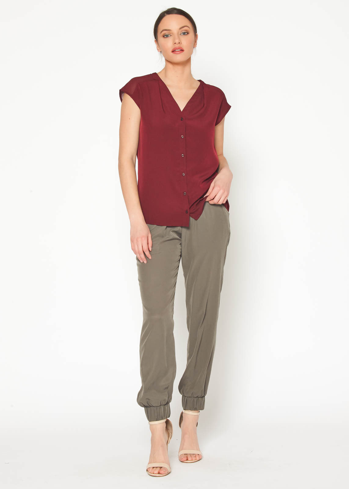 Women's burgundy sleeveless V neck button top displayed on a mannequin, showcasing its elegant design and fabric texture.