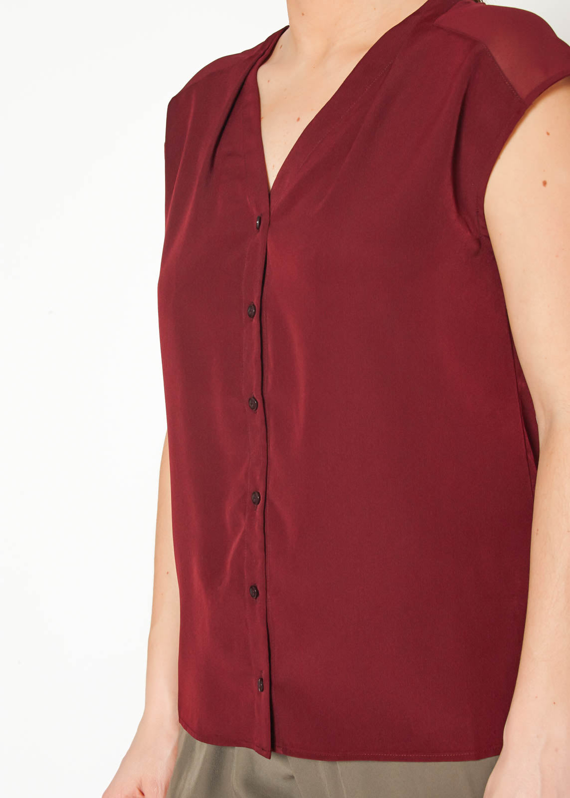 Women's burgundy sleeveless V neck button top displayed on a mannequin, showcasing its elegant design and fabric texture.