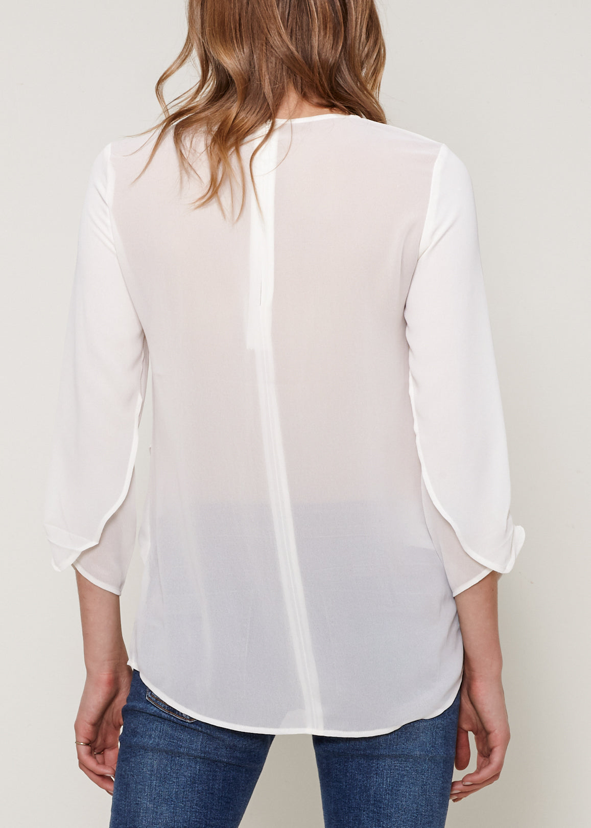 Women's Cross Hem Blouse featuring a surplice hem and gathered cuff details, made from lightweight polyester.