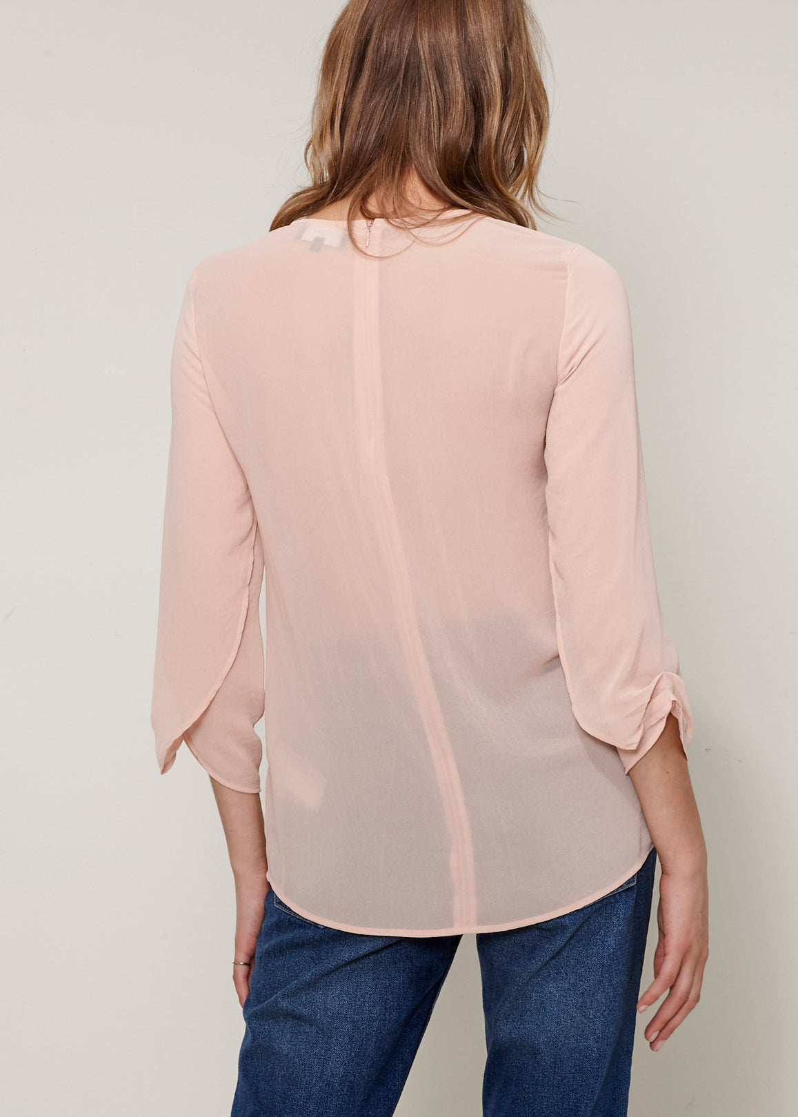 Women's Cross Hem Blouse featuring a surplice hem and gathered cuff details, made from lightweight polyester.