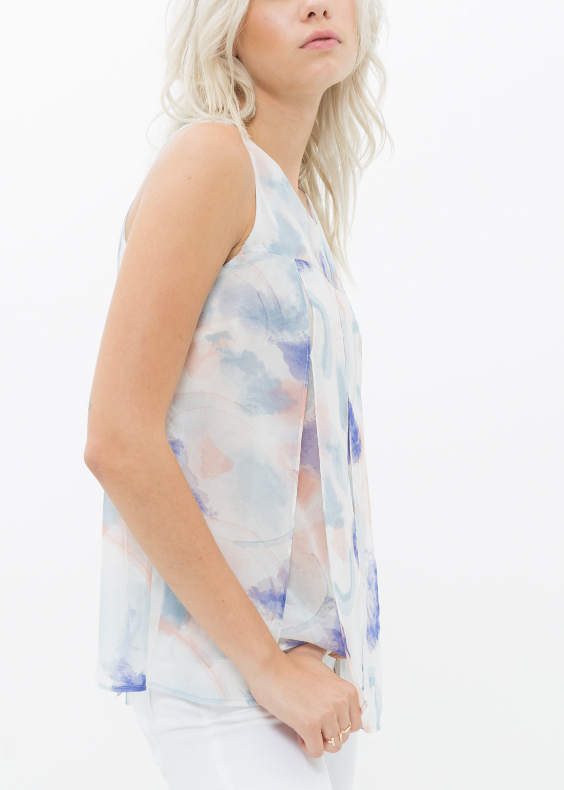 A stylish women's sleeveless blouse featuring a vibrant water color pattern and elegant slit detail, perfect for layering or solo wear.