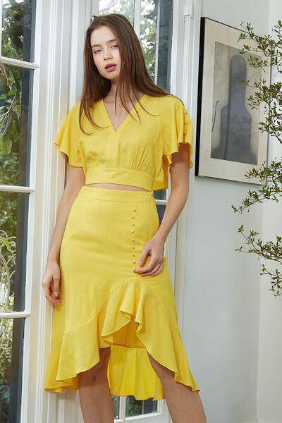 Women's yellow cropped blouse with tie waist and cape sleeves, showcasing a stylish V neckline.