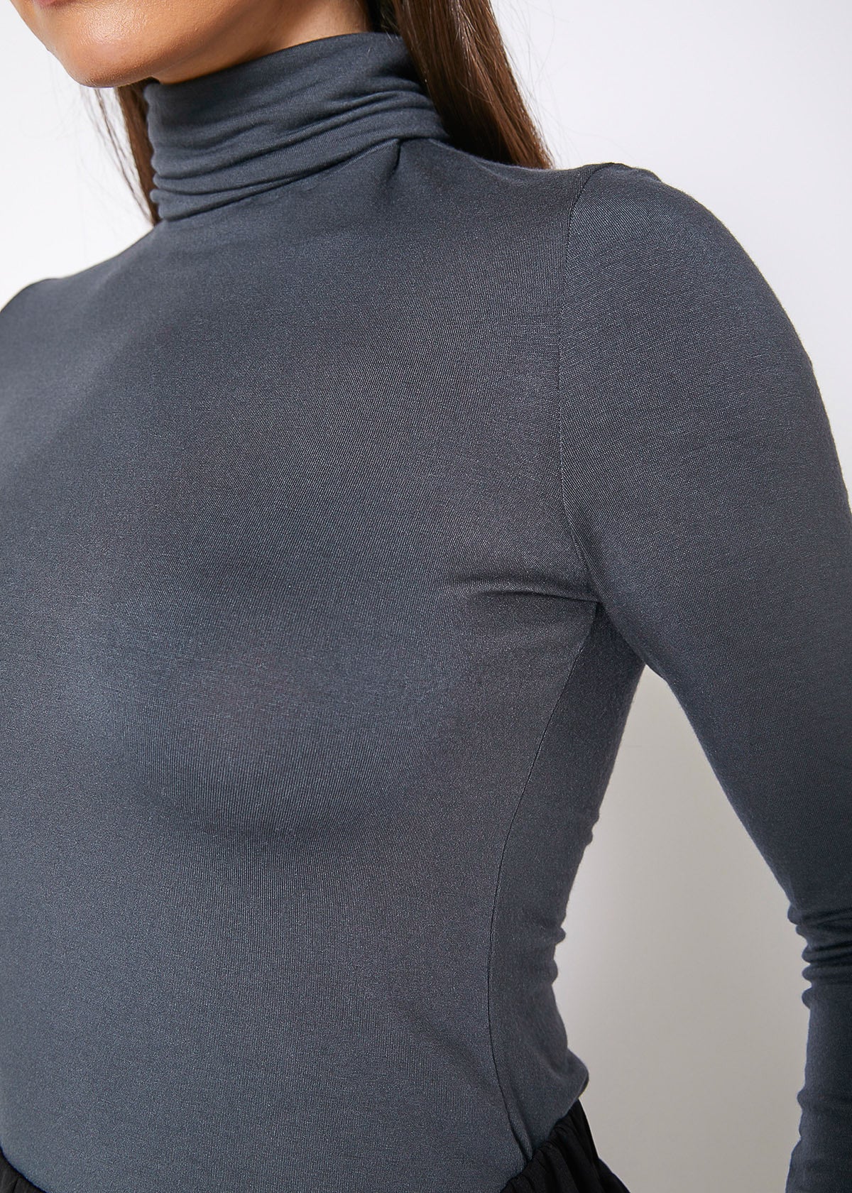 Women's charcoal turtle neck fitted top displayed on a mannequin, showcasing its stylish design and comfortable fit.