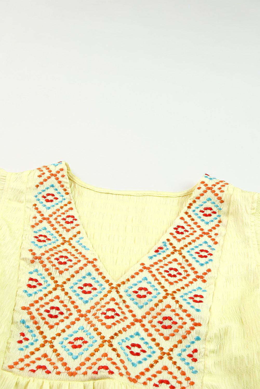 A stylish yellow top featuring geometric embroidery and ruffles, perfect for fashion-forward women.