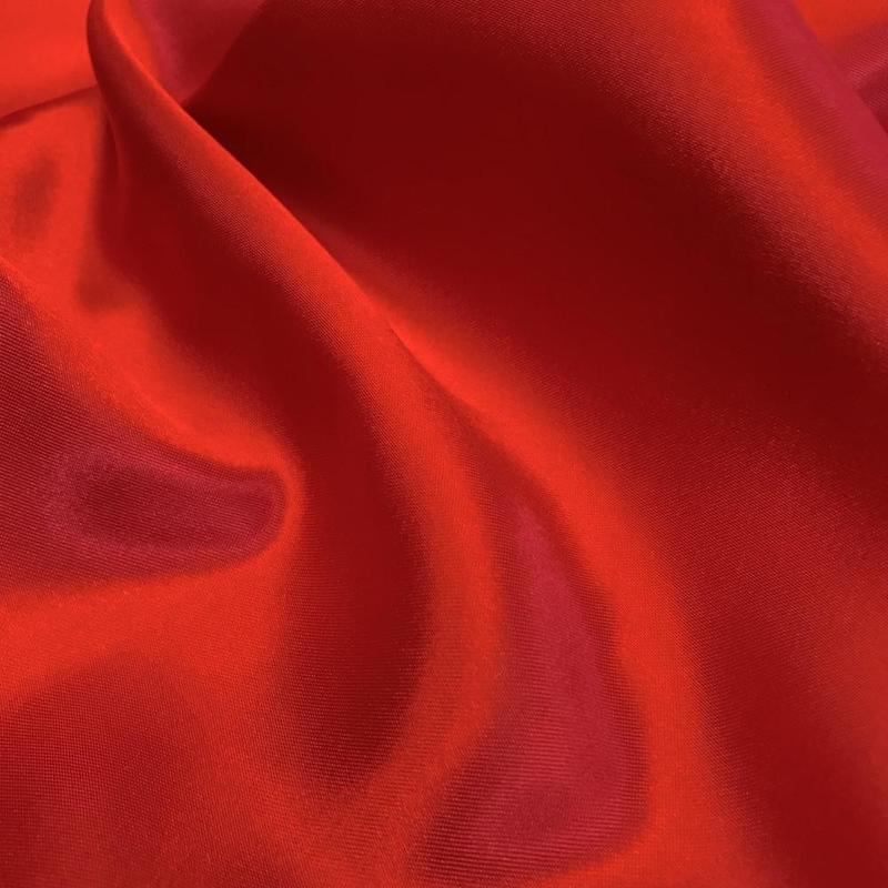 1/2 yard of red charmeuse satin fabric, showcasing its shiny surface and soft texture, ideal for garments and decor.