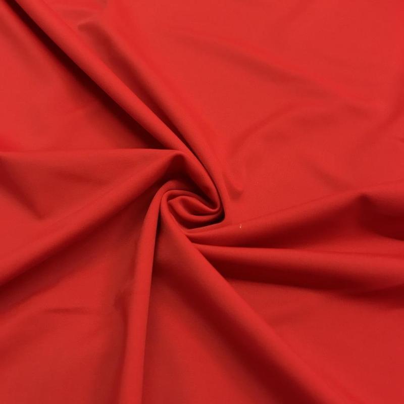 1/2 yard of vibrant red nylon tricot fabric, showcasing its smooth texture and stretch.