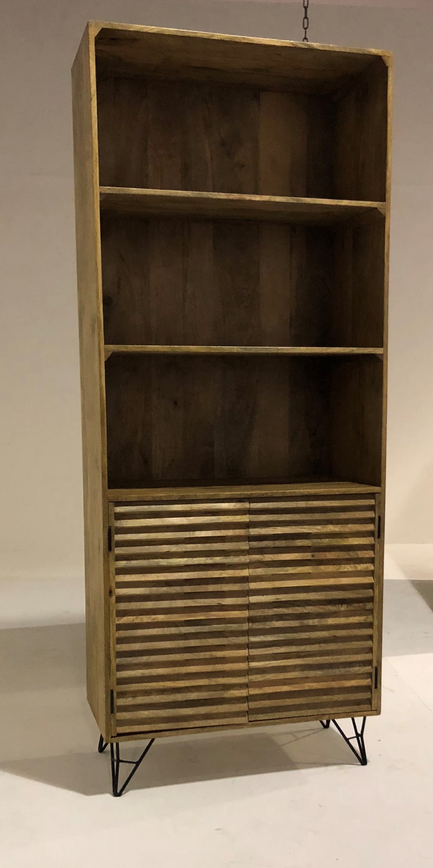 A rustic 17" X 33" X 82" Natural Iron Wood Bookshelf featuring three open shelves and two closed compartments, supported by origami-styled iron legs.