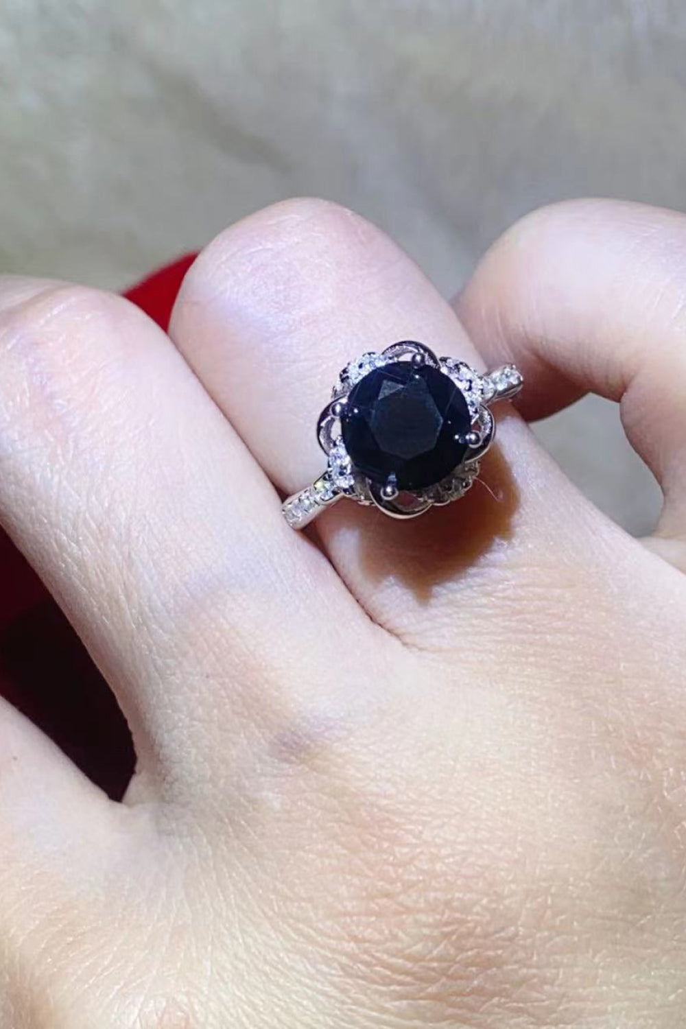 A beautiful 2 Carat Black Moissanite Floral Ring displayed in a flat lay style, showcasing its modern minimalist design and sparkling moissanite stone.