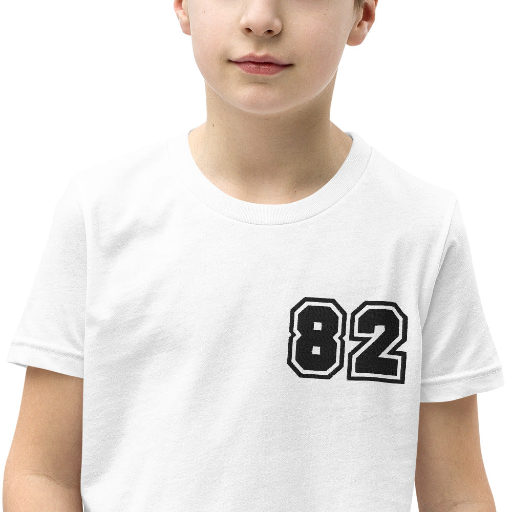 A youth wearing the 2882Junior™ Greeky Prepster '82' Short Sleeve T-Shirt, showcasing its unique design and relaxed fit.