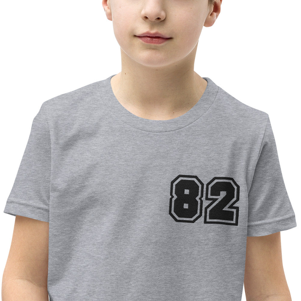 A youth wearing the 2882Junior™ Greeky Prepster '82' Short Sleeve T-Shirt, showcasing its unique design and relaxed fit.