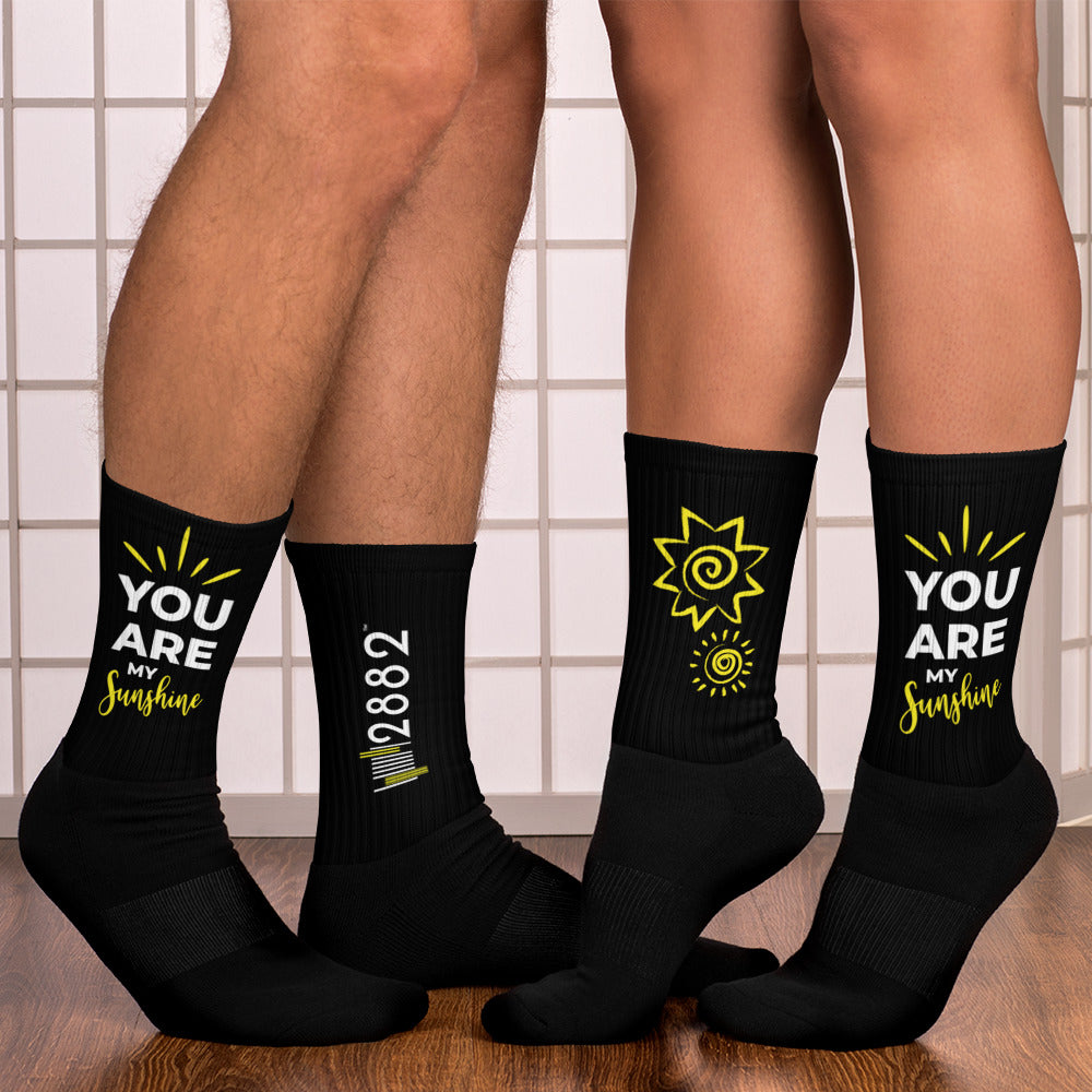 A pair of 2882Sport™ You Are My Sunshine Ribbed Crew Socks featuring vibrant artwork on a black background with a cushioned bottom.