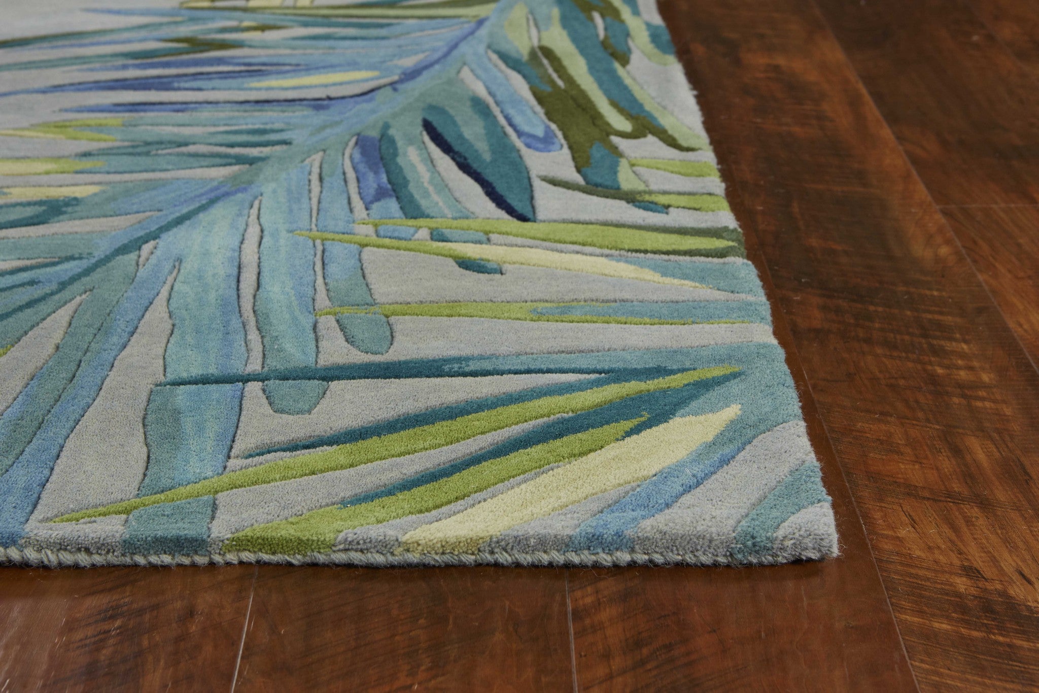 A beautiful 4x6 grey blue hand tufted area rug featuring tropical palm designs, perfect for indoor living spaces.