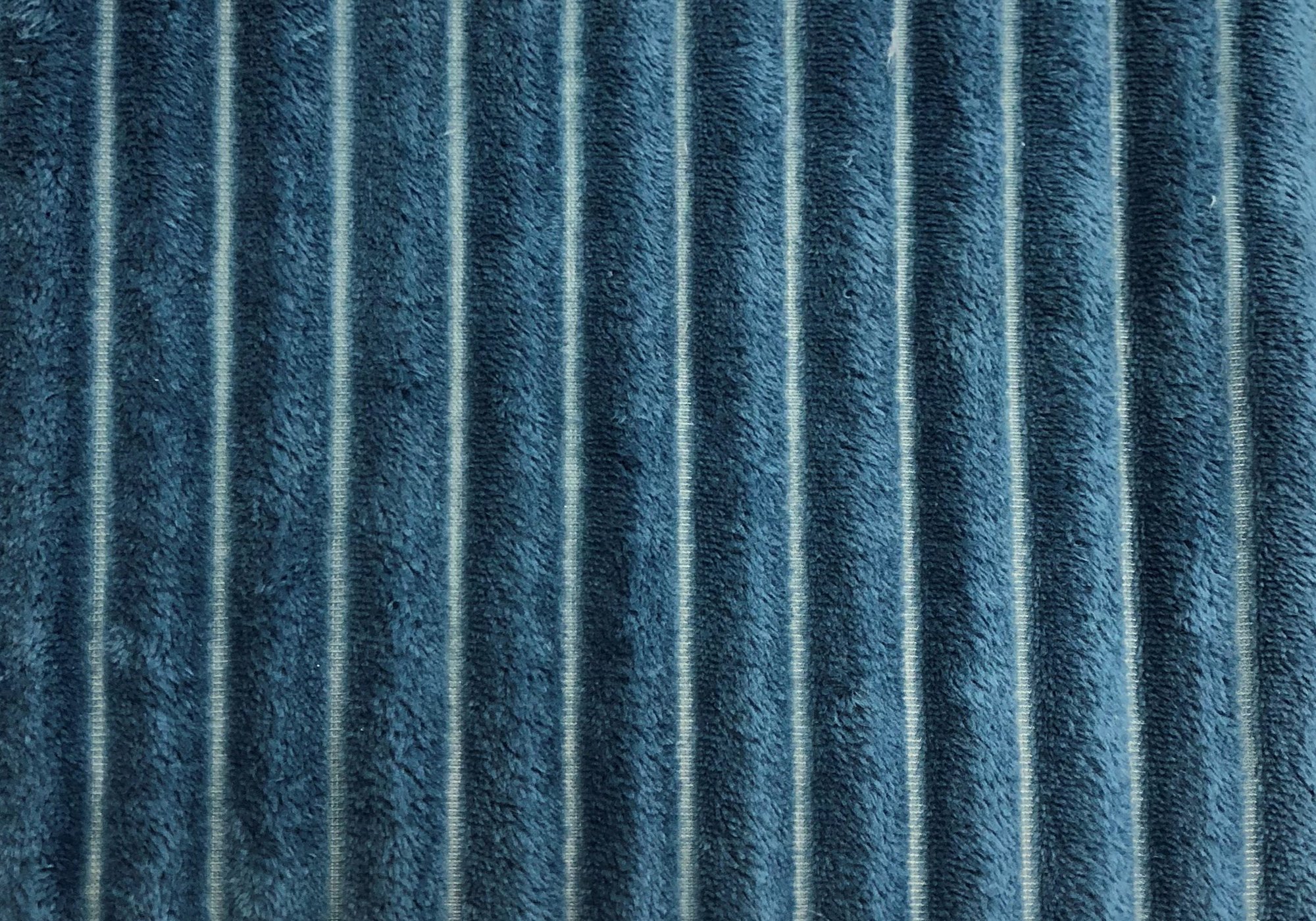 A cozy 50" x 60" blue ultra soft ribbed throw blanket draped elegantly over a sofa, showcasing its contemporary design and plush texture.