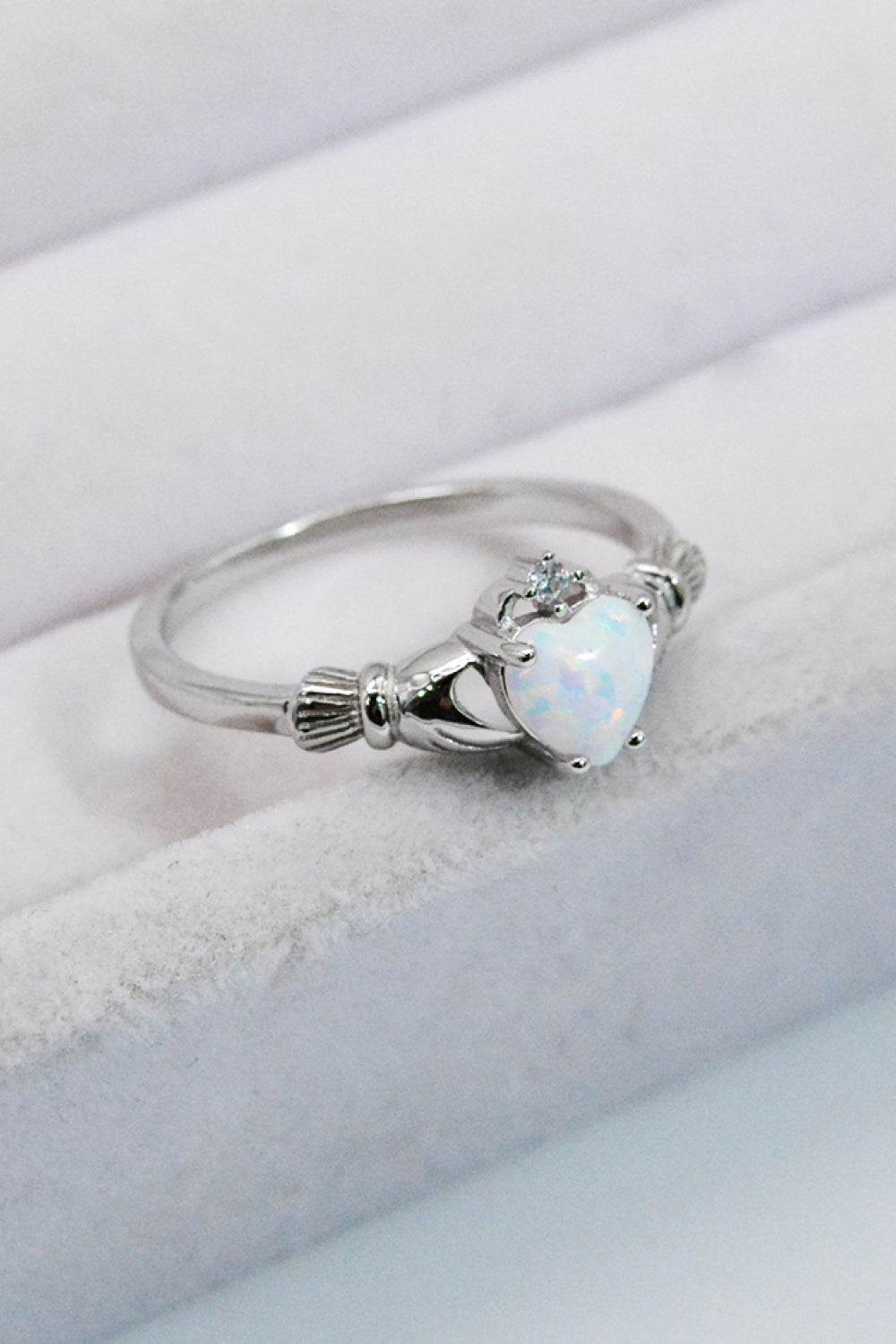 A polished 925 sterling silver heart opal ring displayed in a flat lay style, showcasing its modern design and vibrant opal centerpiece.