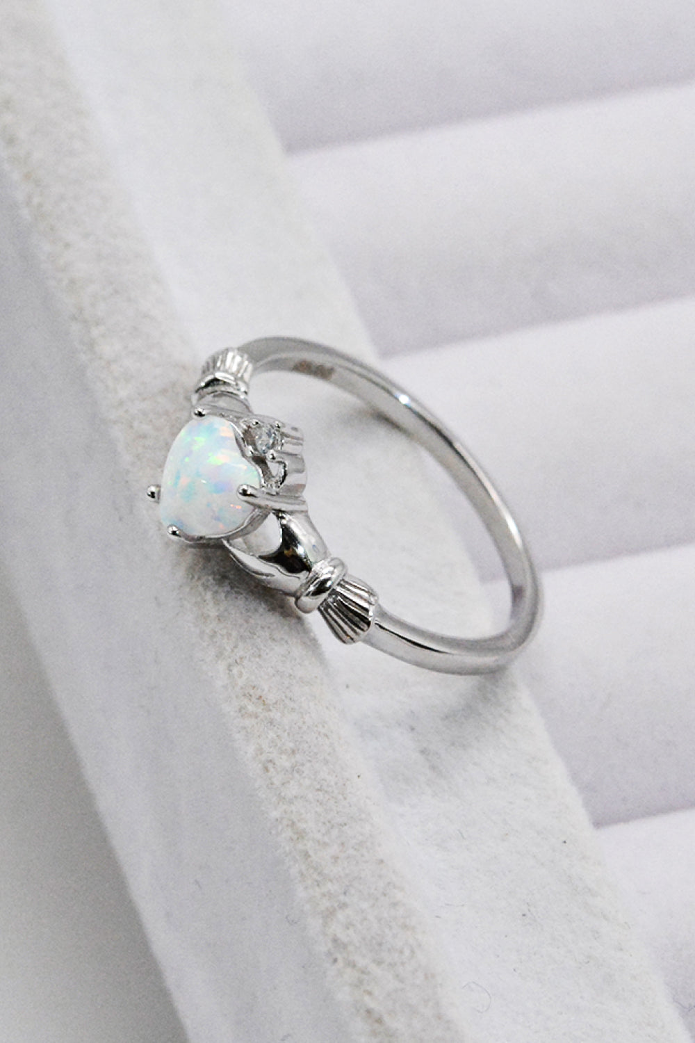 A polished 925 sterling silver heart opal ring displayed in a flat lay style, showcasing its modern design and vibrant opal centerpiece.