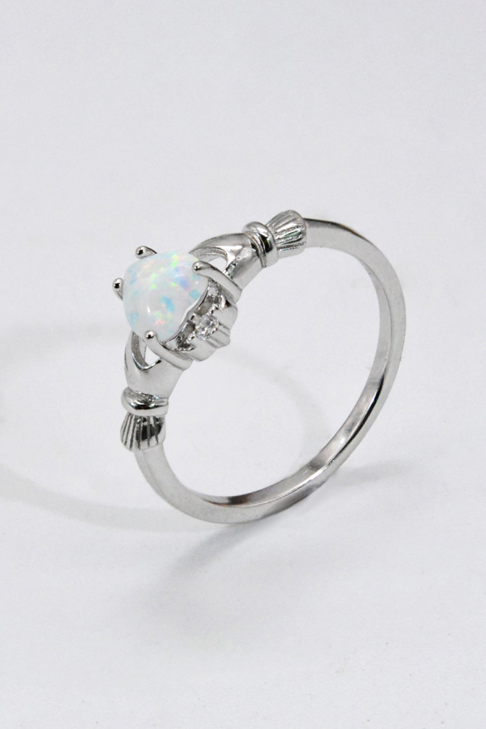 A polished 925 sterling silver heart opal ring displayed in a flat lay style, showcasing its modern design and vibrant opal centerpiece.