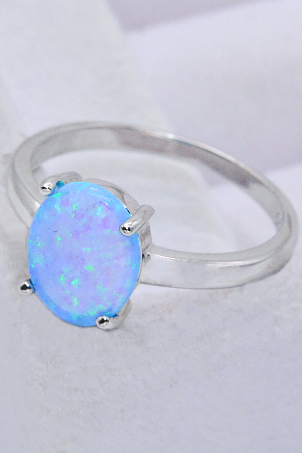 A minimalist 925 sterling silver opal solitaire ring with a polished finish, showcasing a vibrant opal gemstone.