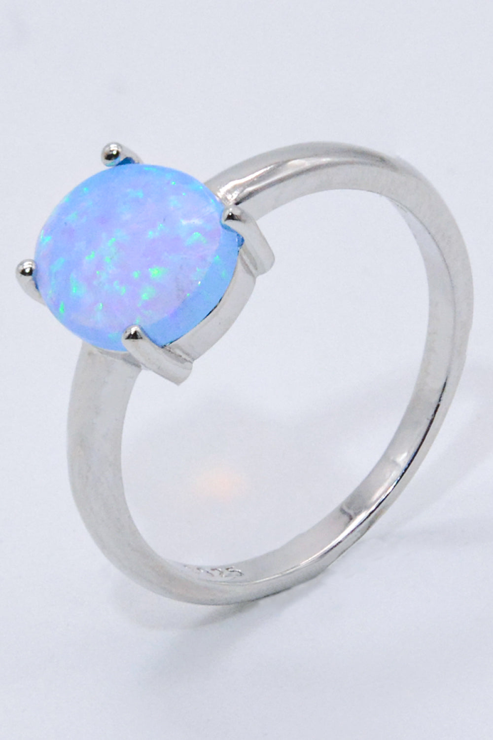 A minimalist 925 sterling silver opal solitaire ring with a polished finish, showcasing a vibrant opal gemstone.