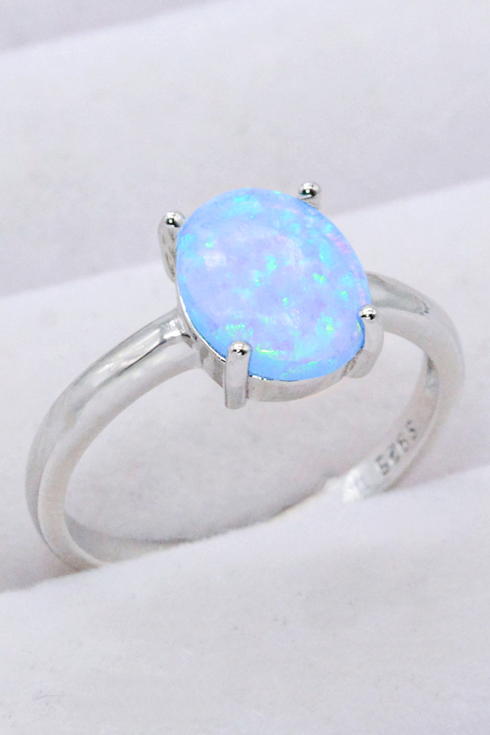 A minimalist 925 sterling silver opal solitaire ring with a polished finish, showcasing a vibrant opal gemstone.