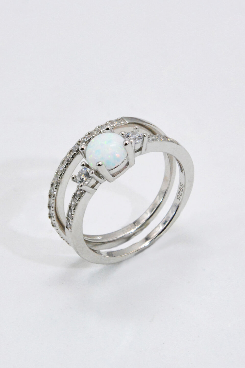 A modern 925 sterling silver opal split shank ring displayed in a flat lay style, showcasing its minimalist design and polished finish.