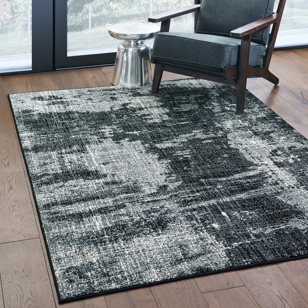 A modern 9x12 black and ivory abstract area rug, showcasing a distressed pattern, perfect for indoor use.