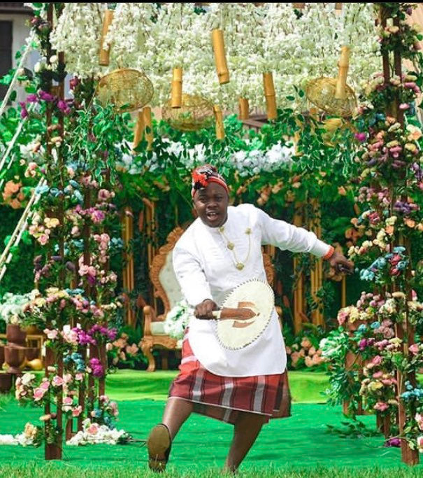 A complete set of African Groomsmen Attire including a shirt, wrapper, hat, necklace, bracelet, linking button stud, and staff, showcasing vibrant colors and traditional design.