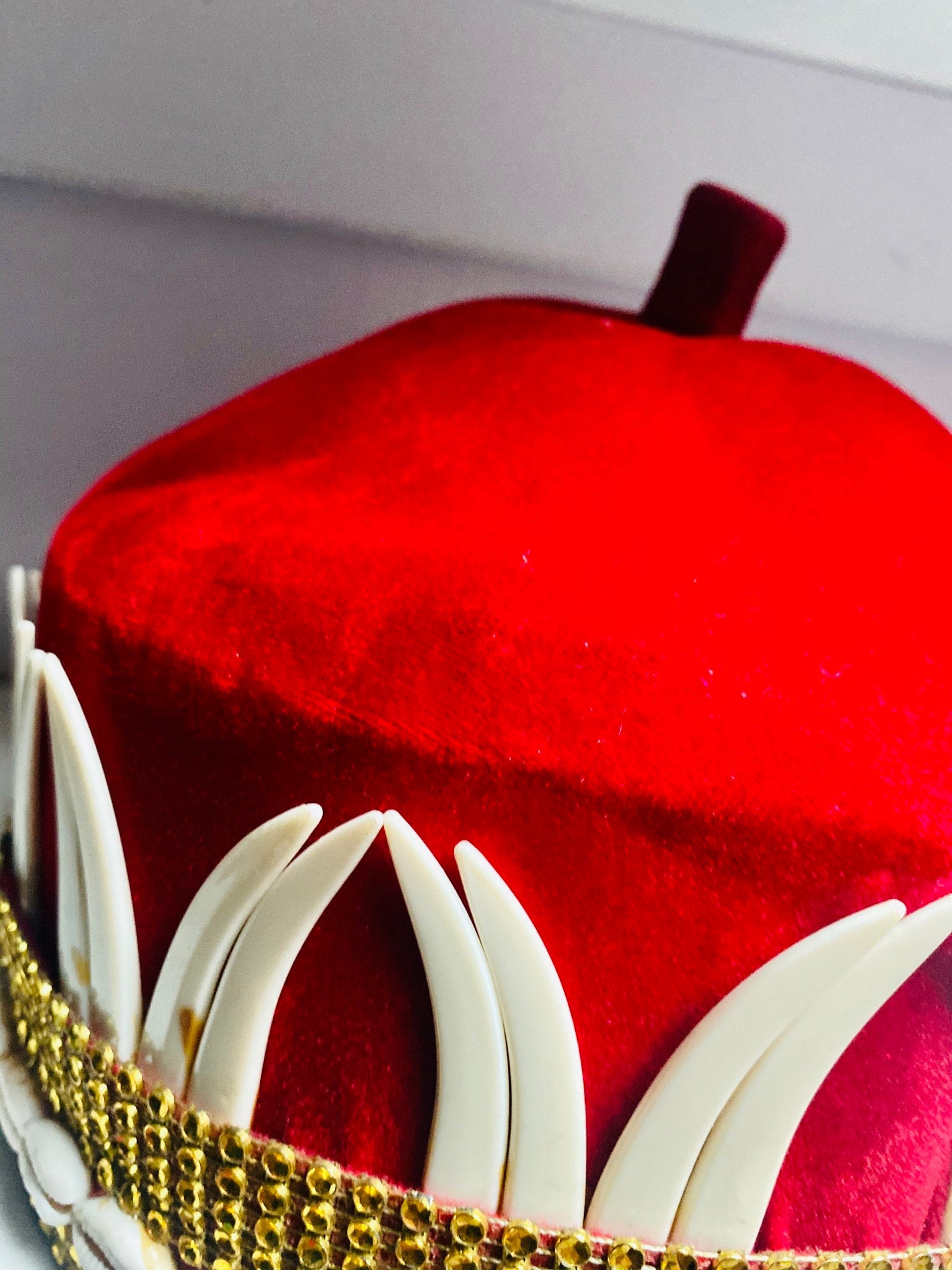 A vibrant red African hat embellished with cowries and tusks, symbolizing cultural heritage and elegance.