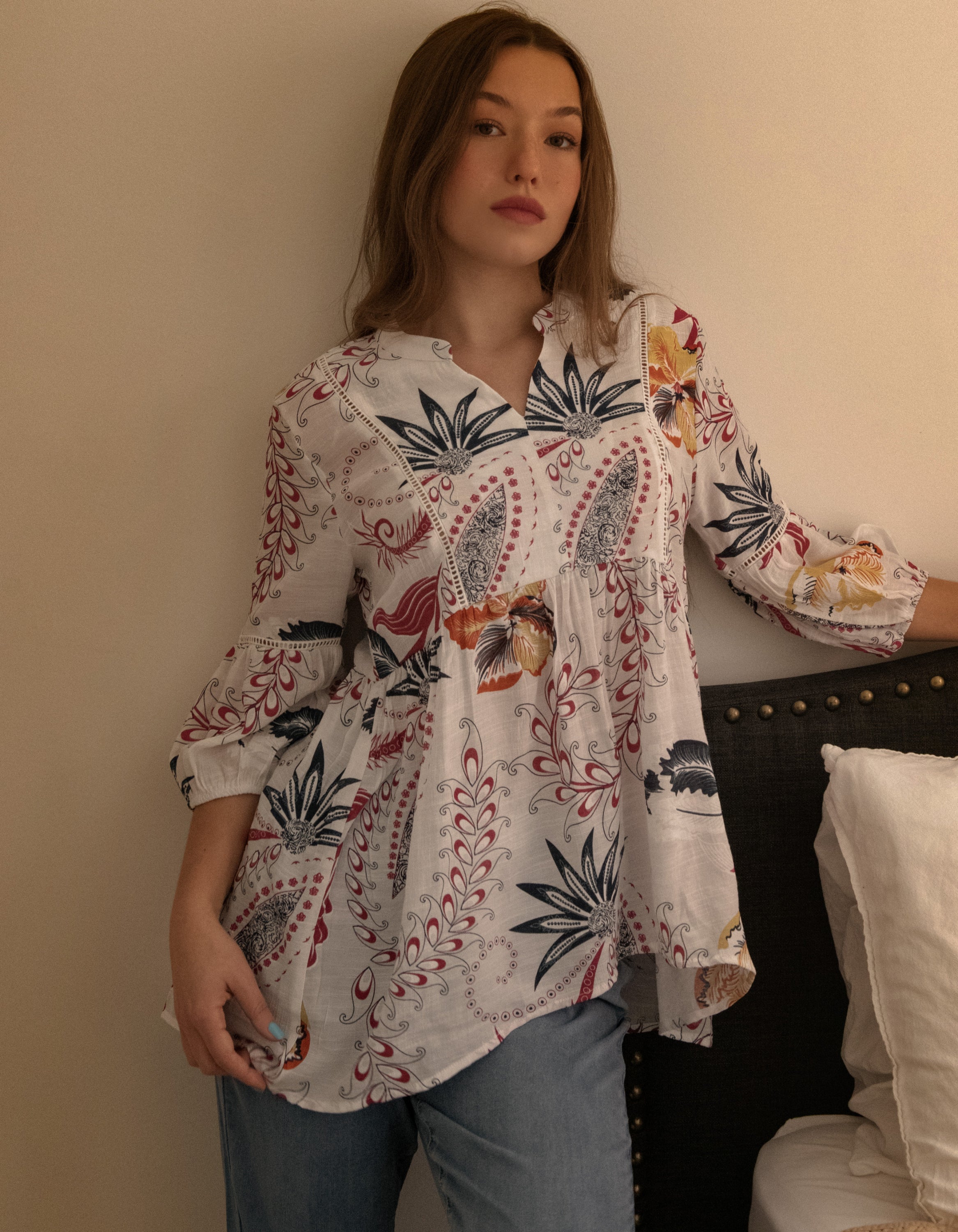 Alba Blouse featuring a white background with colorful foliage print, open V-neck, and stylish high-low hemline.