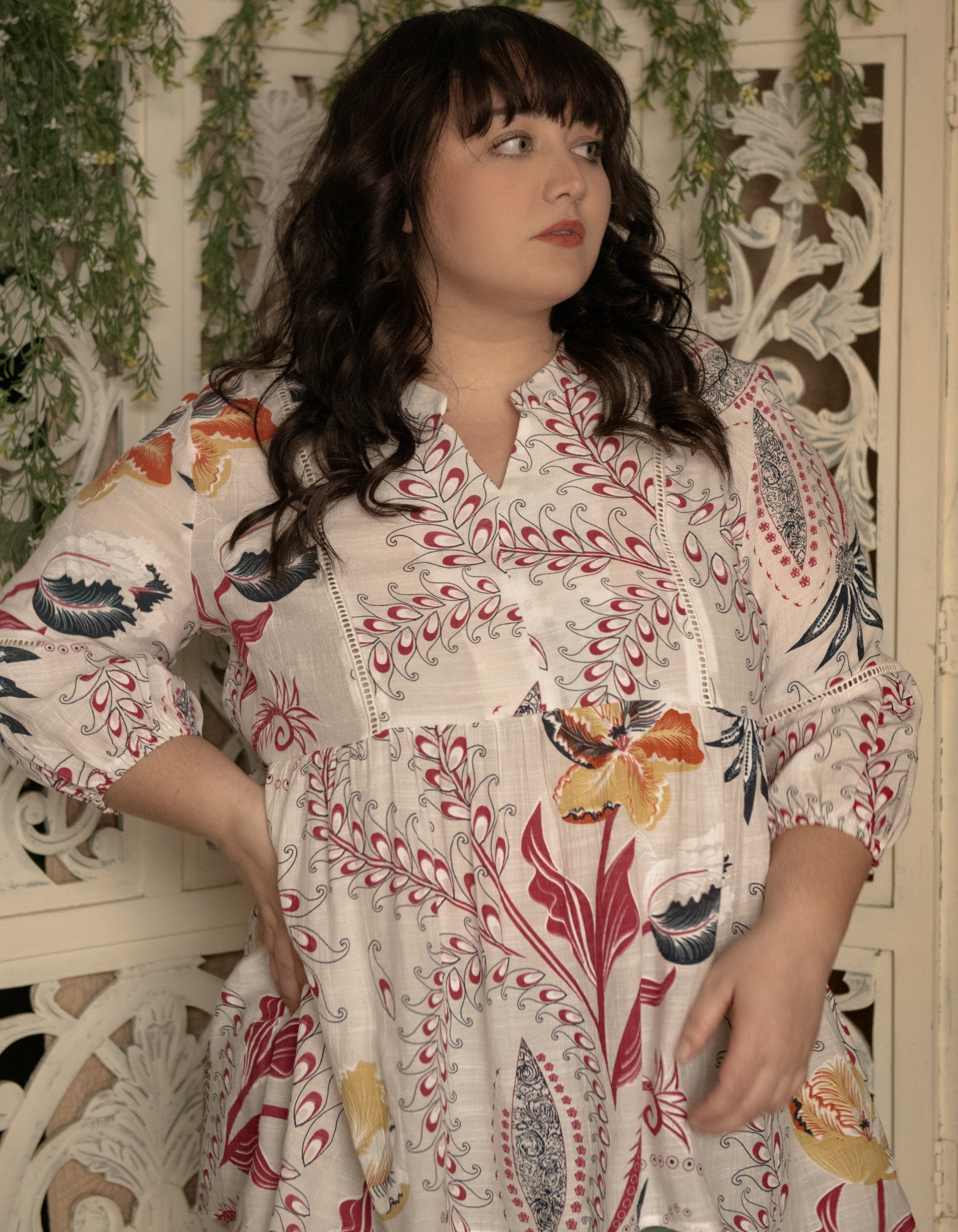 Alba Blouse featuring a white background with colorful foliage print, open V-neck, and stylish high-low hemline.