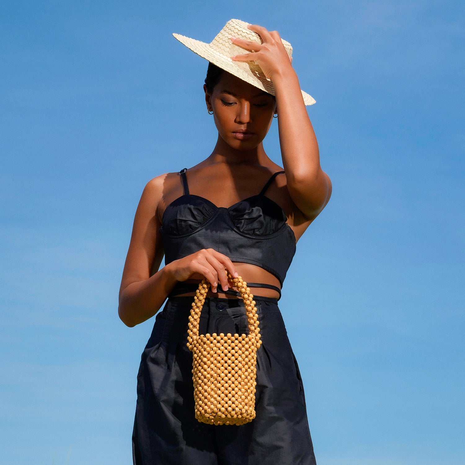 ALILA Wooden Beads Bucket Bag featuring natural wooden beads and a cotton lining, perfect for beach outings.