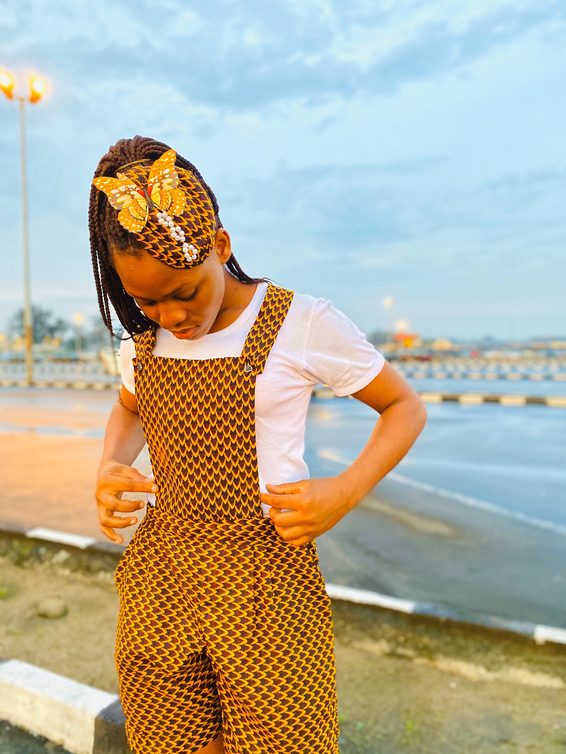 Amaka Playsuit made from fine African wax fabric, featuring vibrant patterns and a matching headpiece.