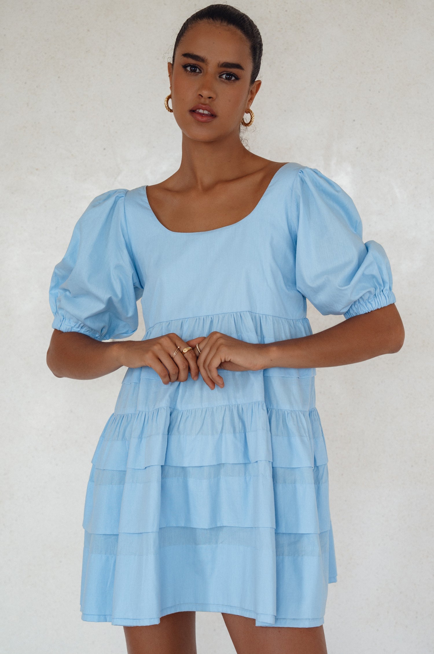 A stylish Andrea Babydoll Cotton Mini Dress featuring elasticated short sleeves, a round neckline, and a flowing hem, perfect for casual or evening wear.