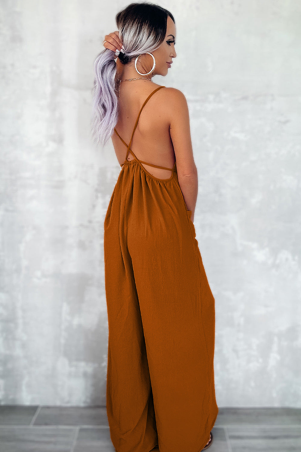 Apricot spaghetti straps jumpsuit with waist tie and pockets, featuring a wide leg design.