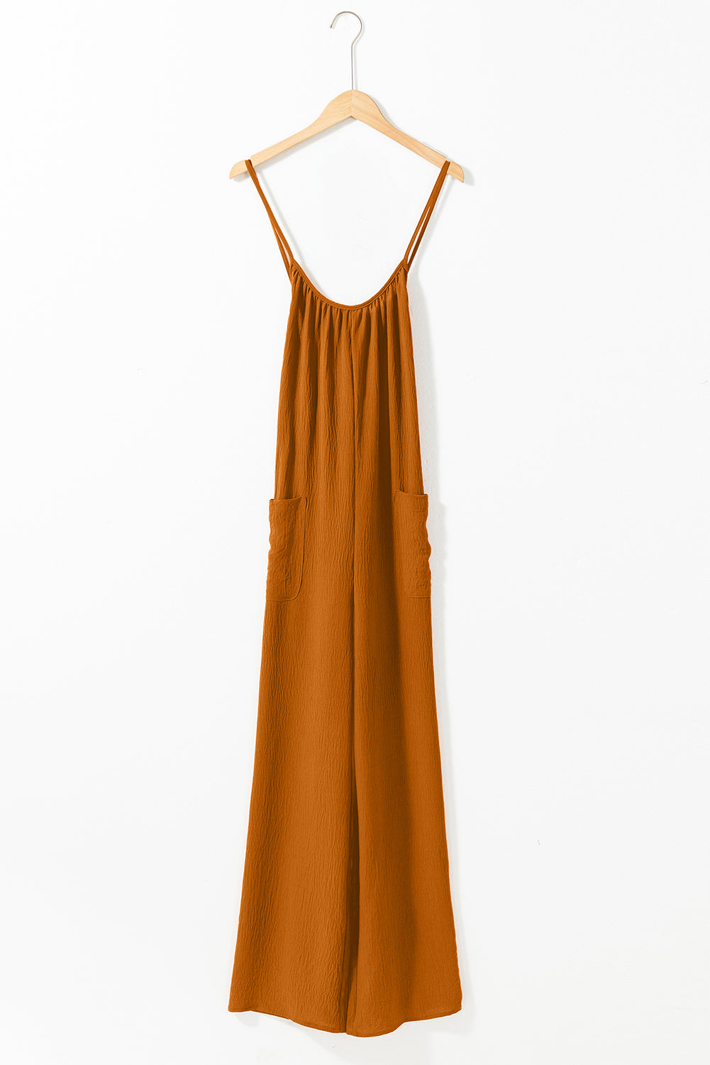 Apricot spaghetti straps jumpsuit with waist tie and pockets, featuring a wide leg design.