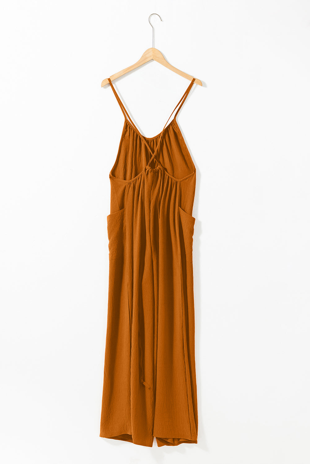 Apricot spaghetti straps jumpsuit with waist tie and pockets, featuring a wide leg design.