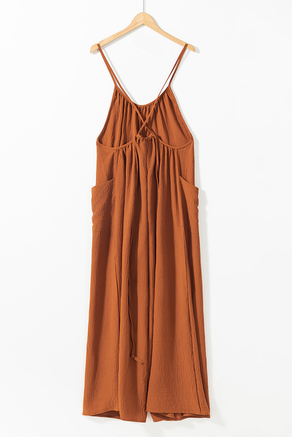 Apricot spaghetti straps jumpsuit with waist tie and pockets, featuring a wide leg design.