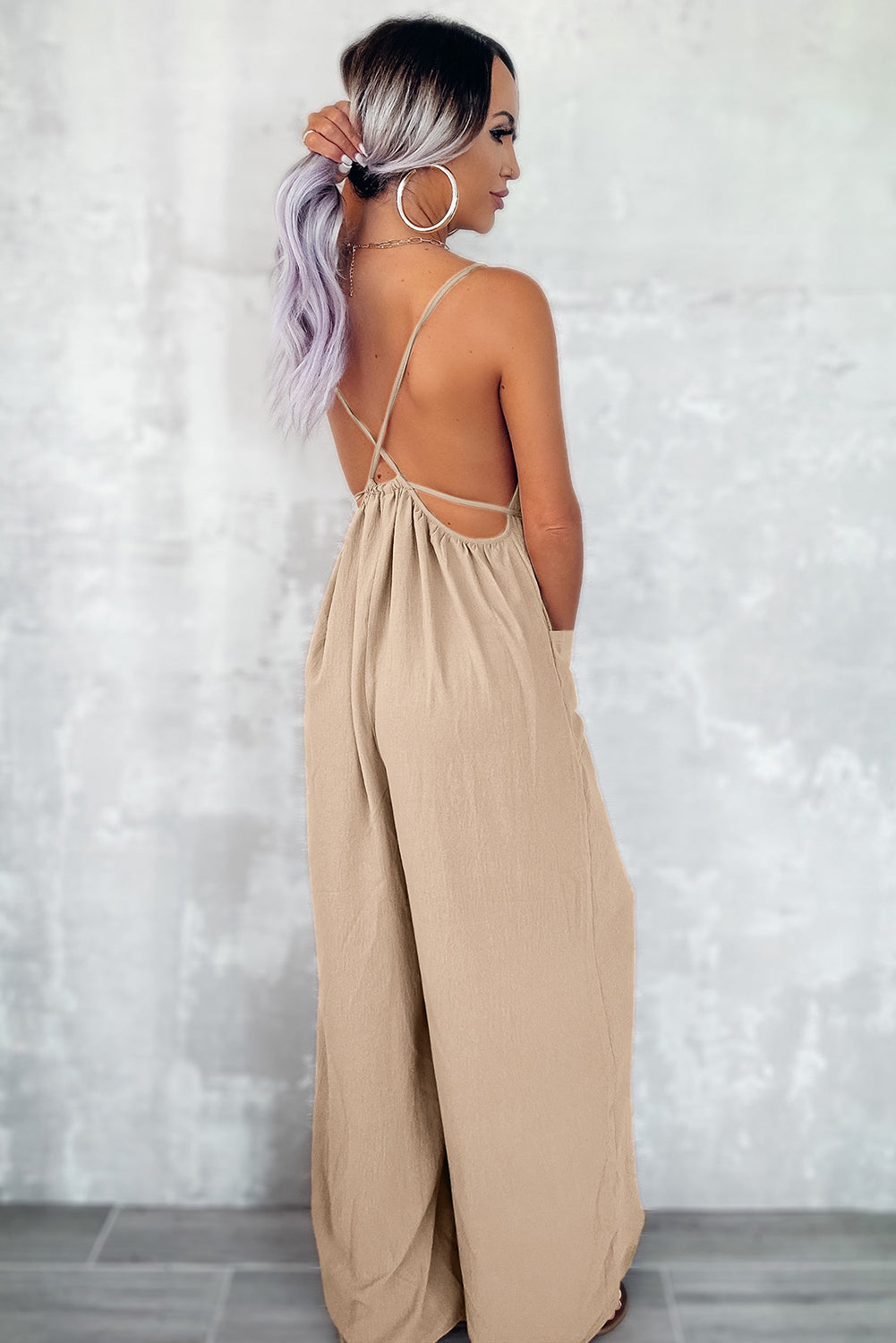 Apricot spaghetti straps jumpsuit with waist tie and pockets, featuring a wide leg design.