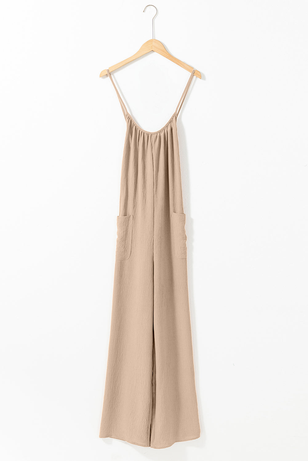 Apricot spaghetti straps jumpsuit with waist tie and pockets, featuring a wide leg design.