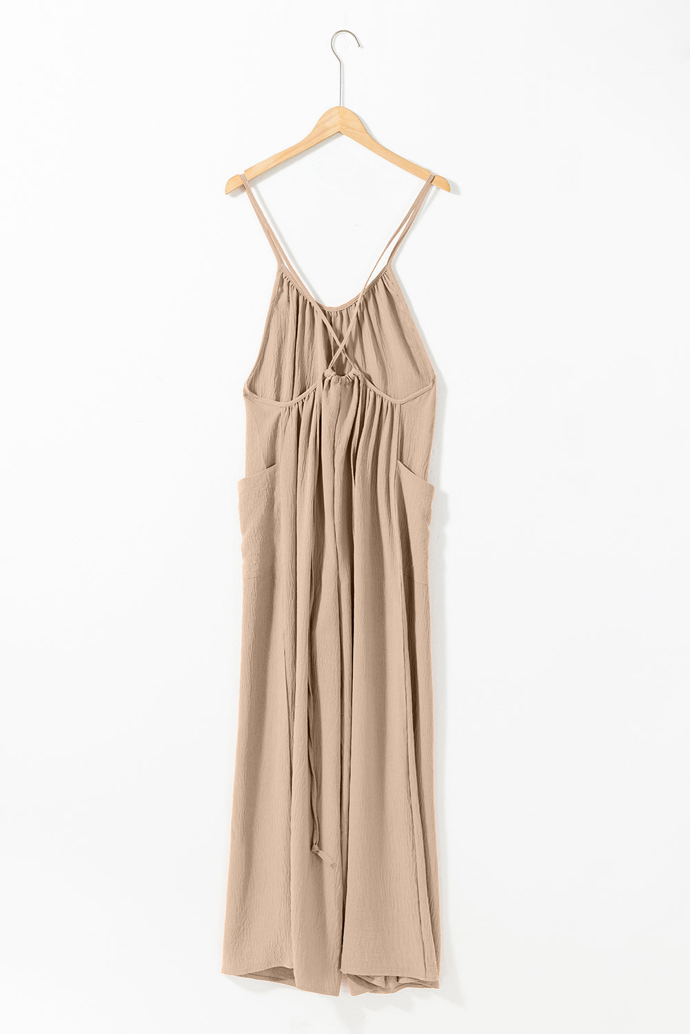 Apricot spaghetti straps jumpsuit with waist tie and pockets, featuring a wide leg design.