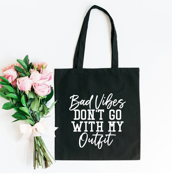 A stylish canvas tote bag with the phrase 'Bad Vibes Don't Go' printed on it, showcasing its durable handles and spacious interior.