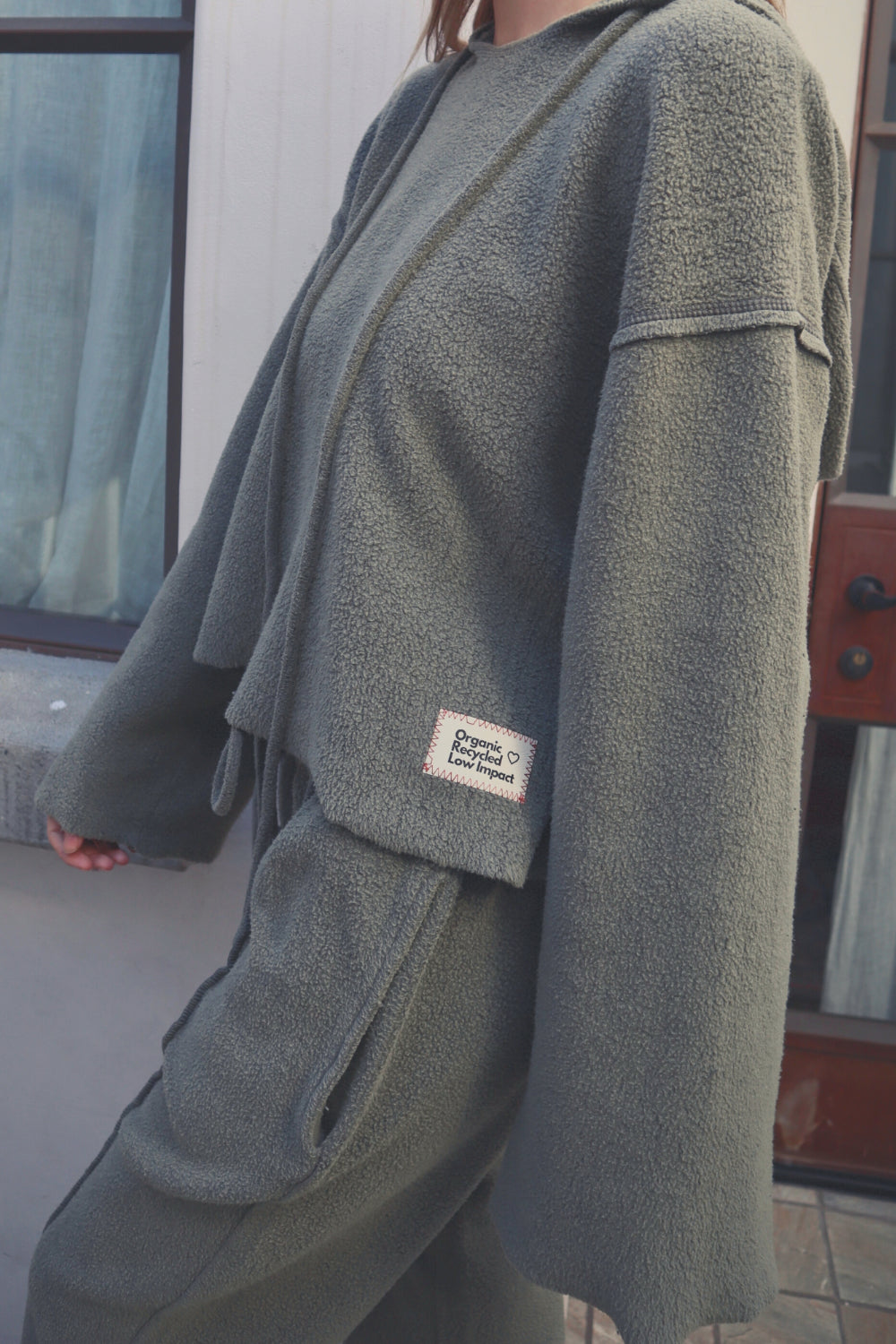 Baja Hoodie in sage green, showcasing its boxy silhouette and eco-friendly fabric, perfect for casual wear.