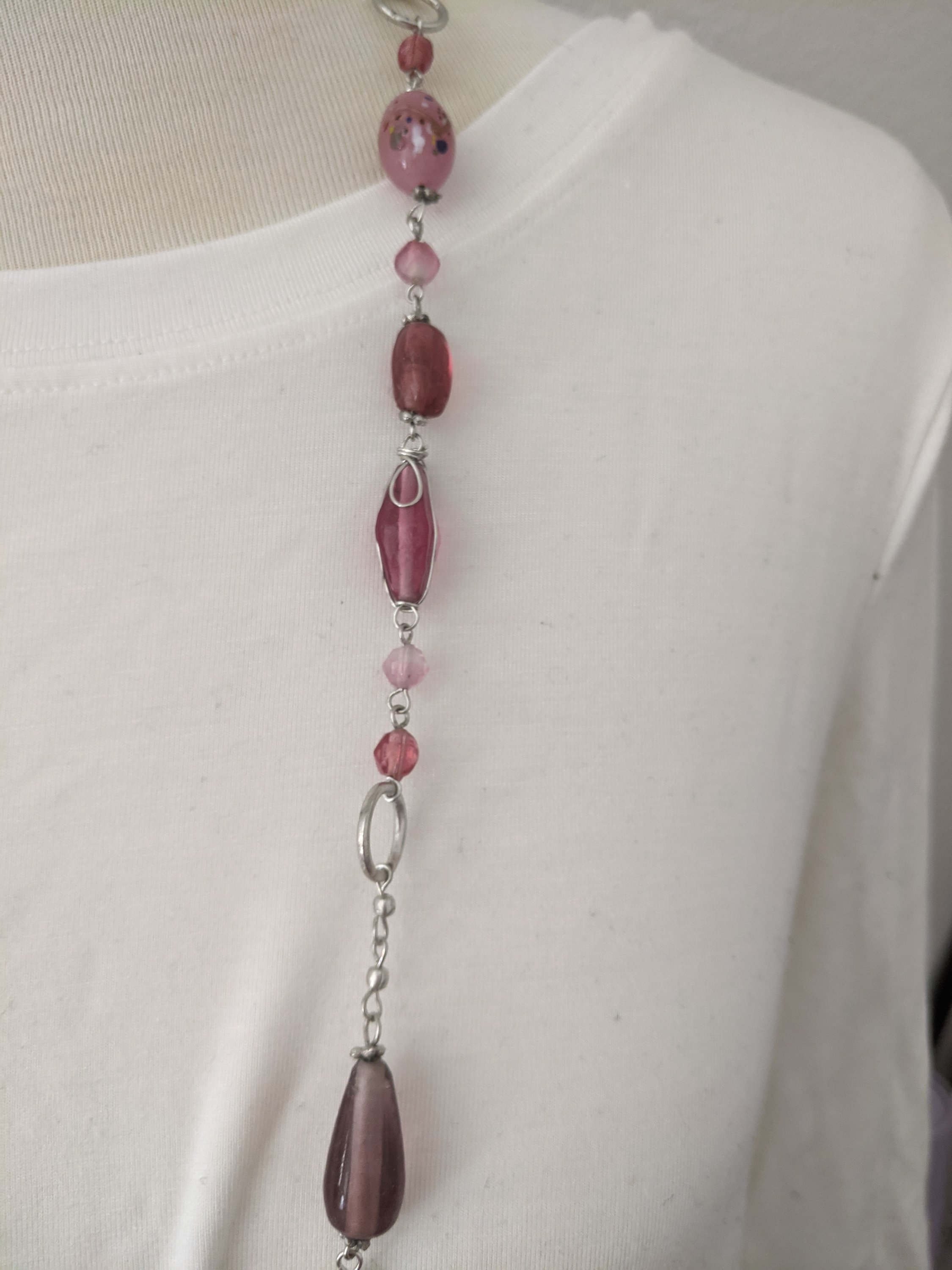 A long silver necklace adorned with beautiful pink stones, showcasing elegance and style.