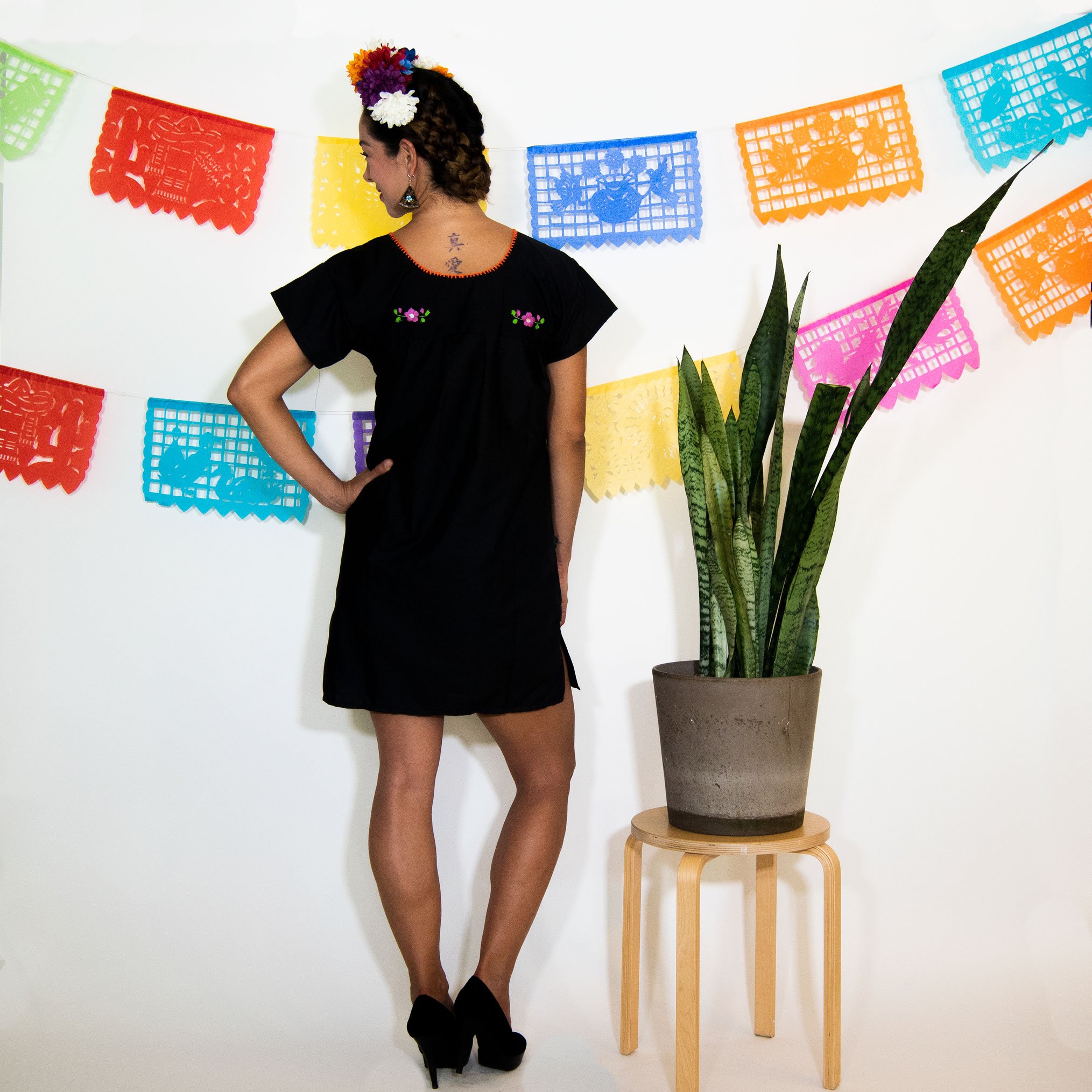 A beautiful Black Mexican Dress adorned with vibrant multicolored flowers, showcasing intricate hand embroidery.