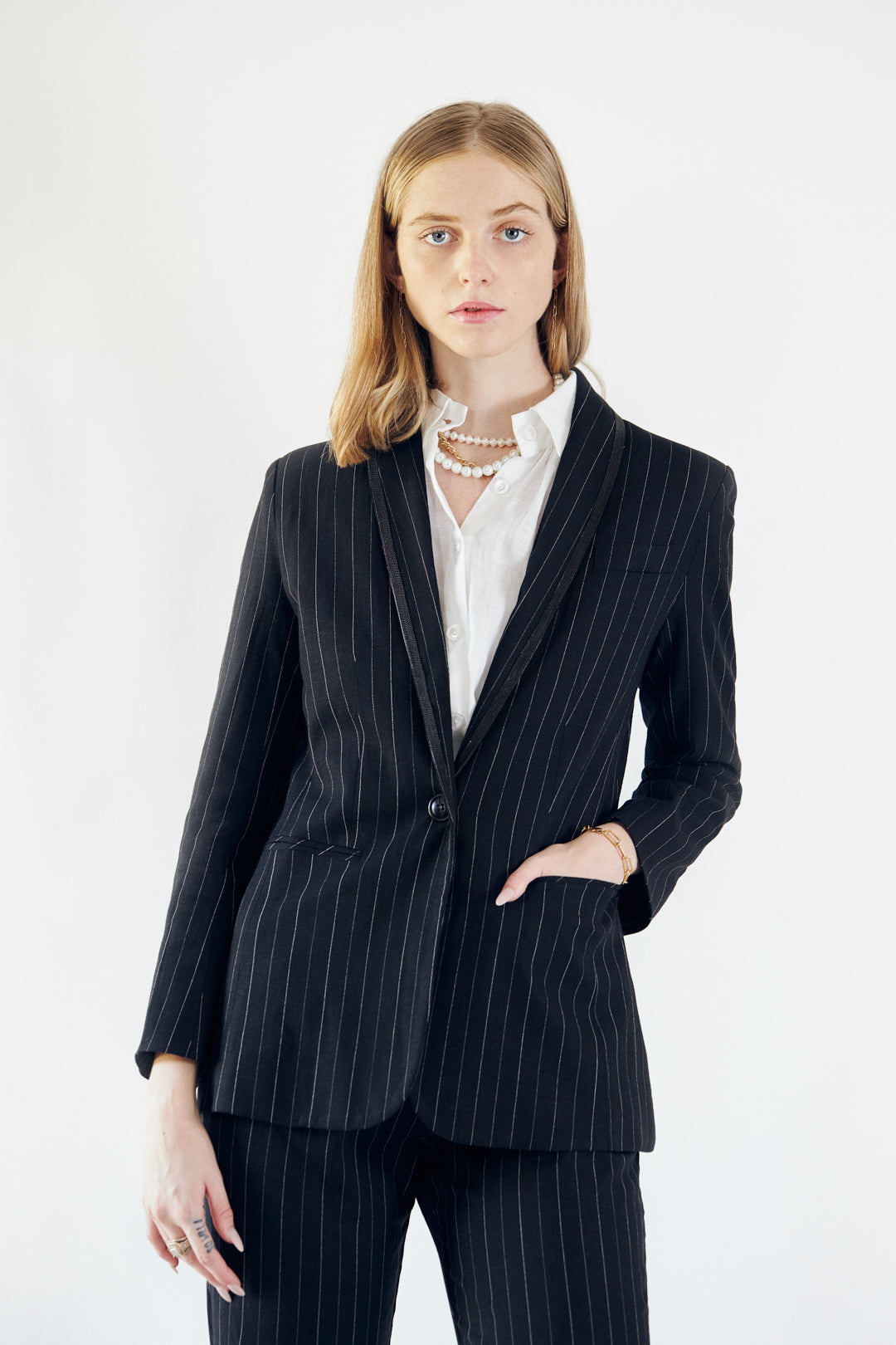 A stylish black blazer with white pinstripes, featuring designed lapels and a single button closure, perfect for professional and casual wear.