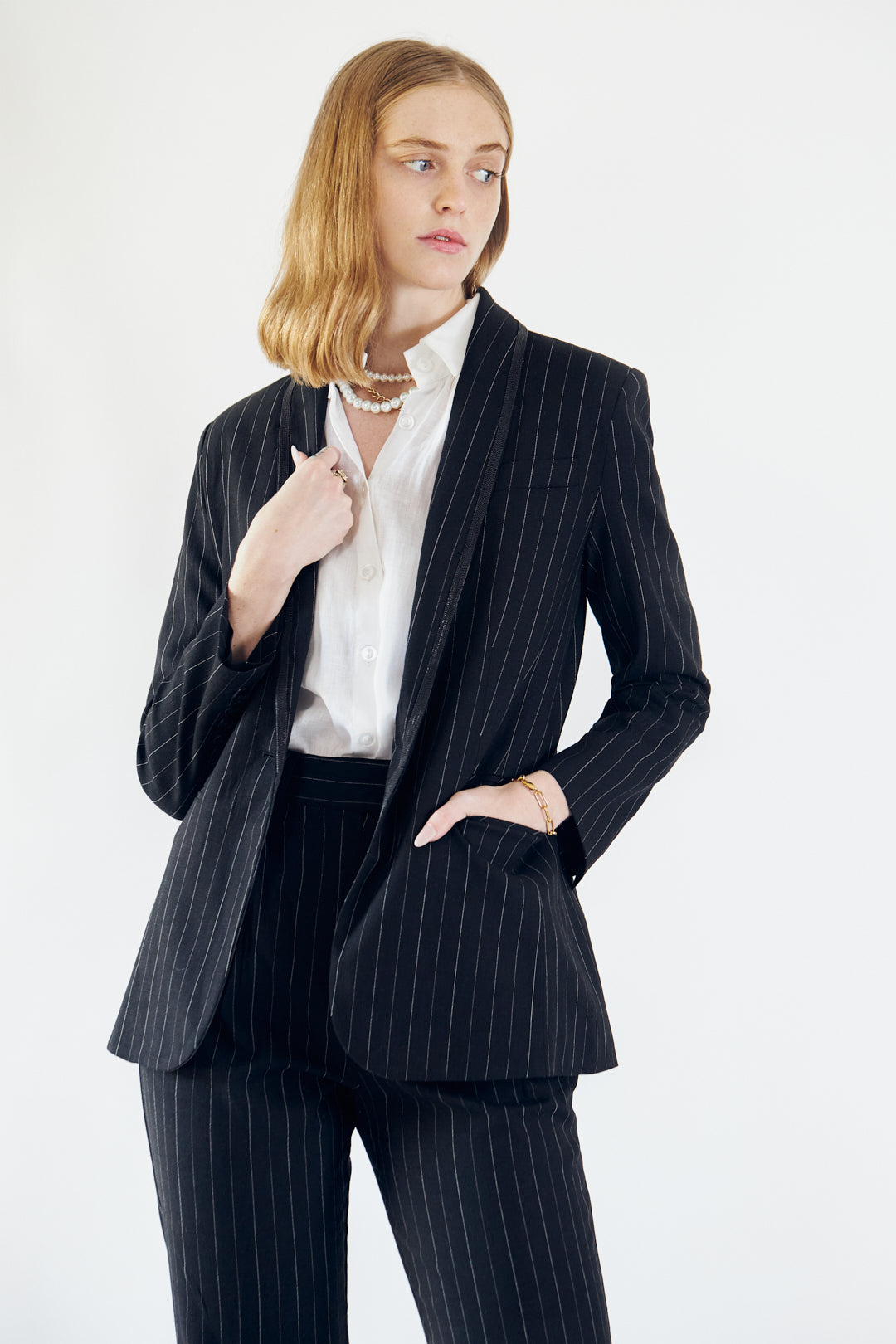 A stylish black blazer with white pinstripes, featuring designed lapels and a single button closure, perfect for professional and casual wear.